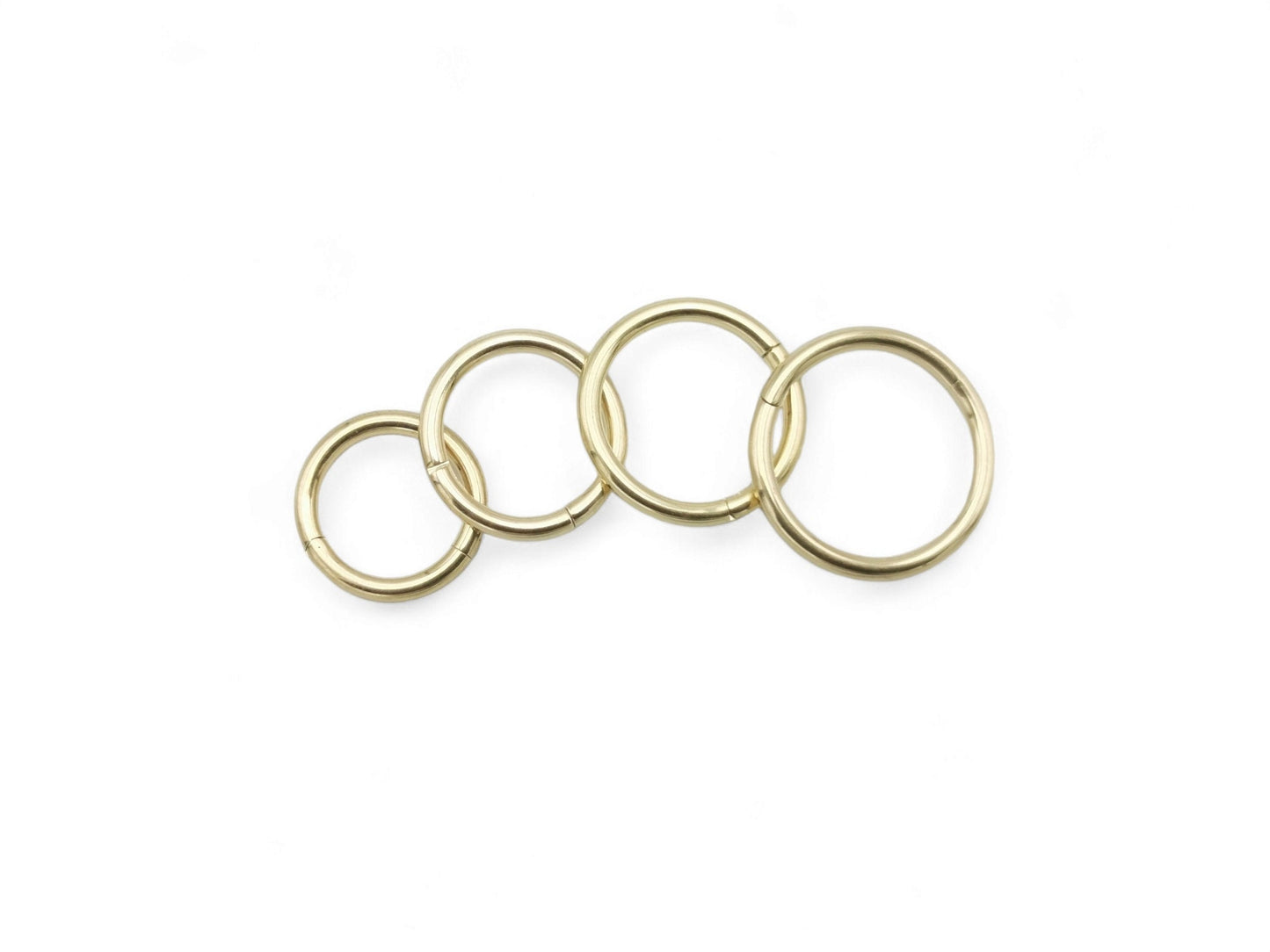 A set of gold-colored titanium clicker rings of different sizes for various body piercings.