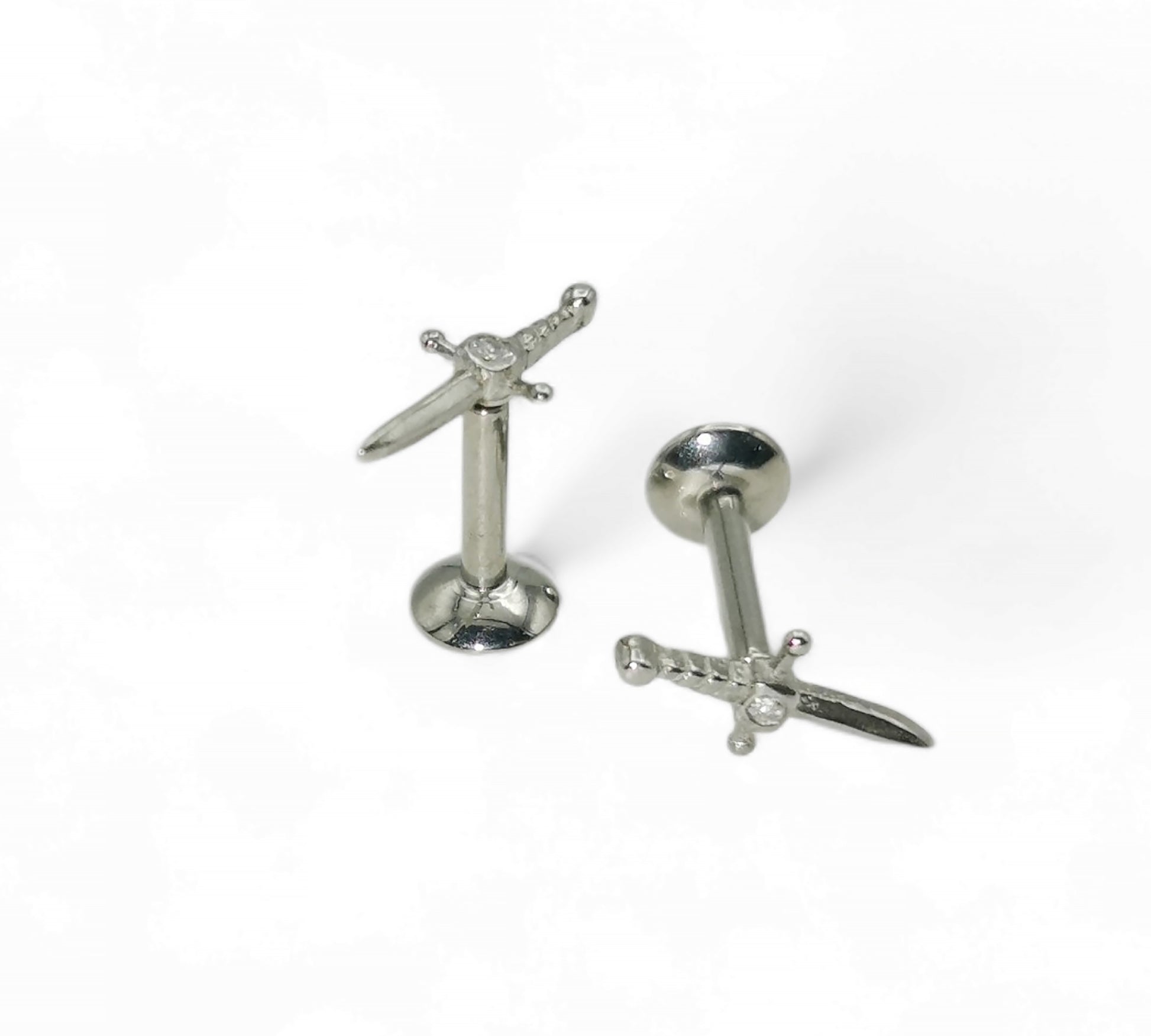 Pair of silver sword-shaped earrings on a white background