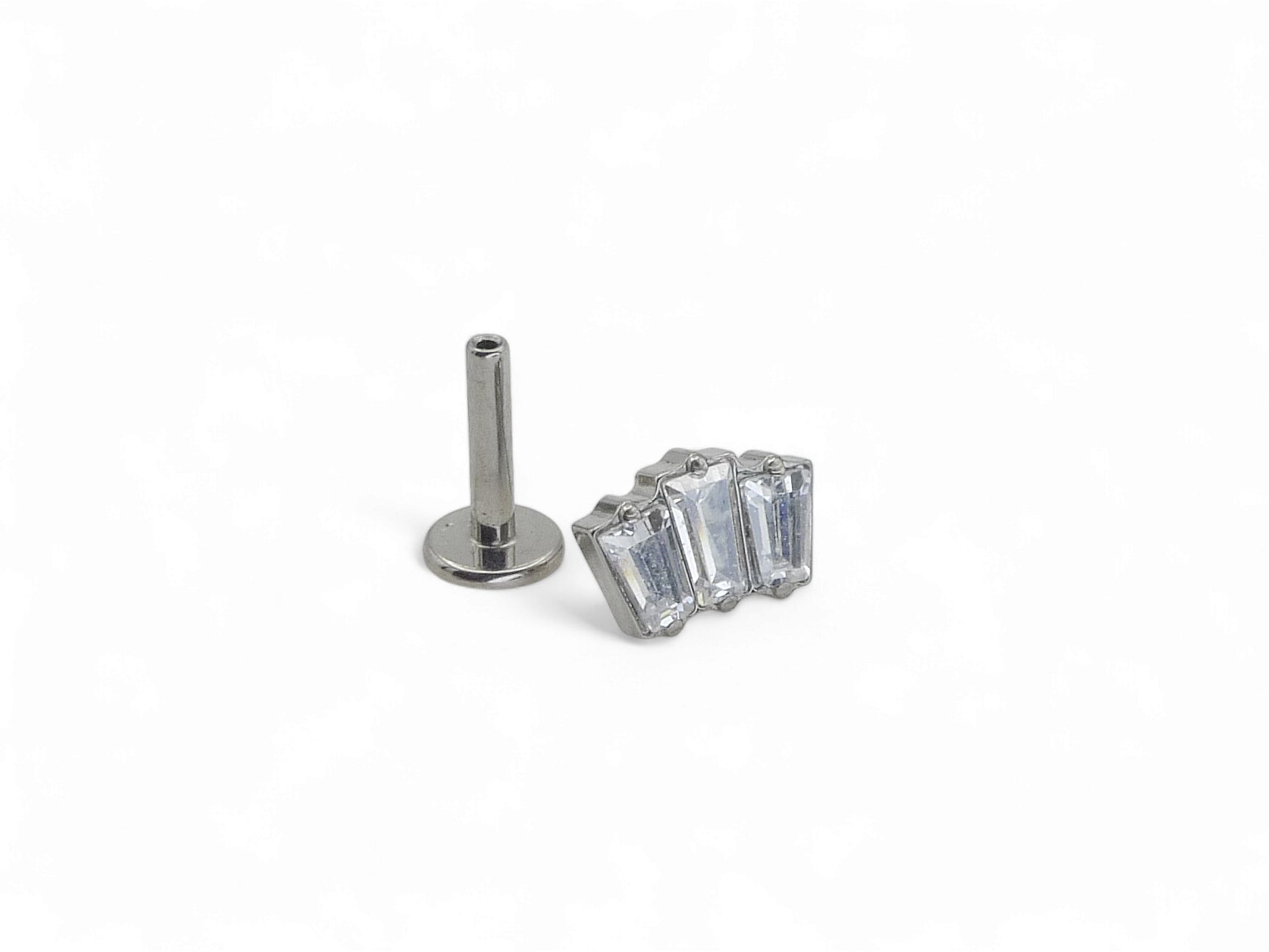 A single titanium push fit baguette cluster stud with multiple clear gemstones, against a white background.
