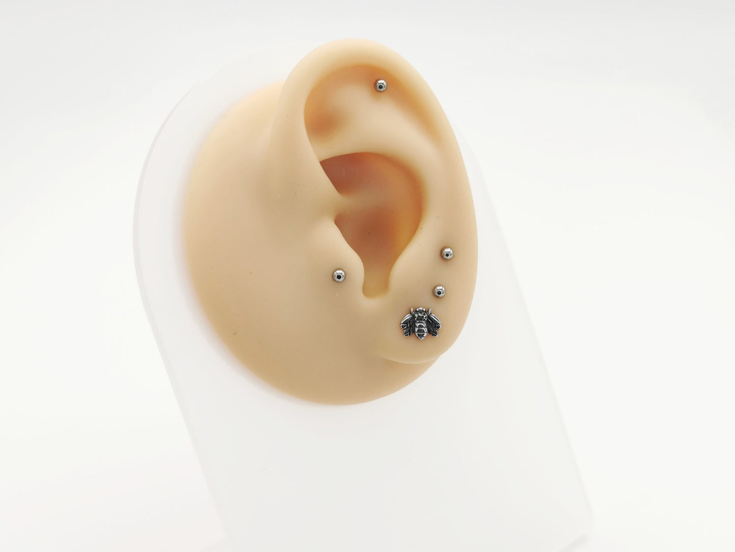 A high-polish finished titanium bee labret stud, with intricate details on the bee's wings and body, on a white background.