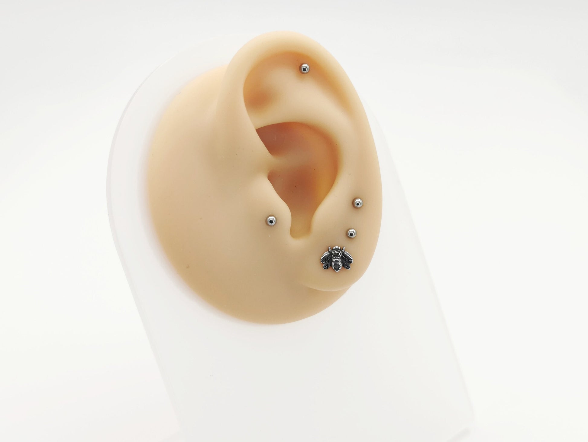 A high-polish finished titanium bee labret stud, with intricate details on the bee's wings and body, on a white background.