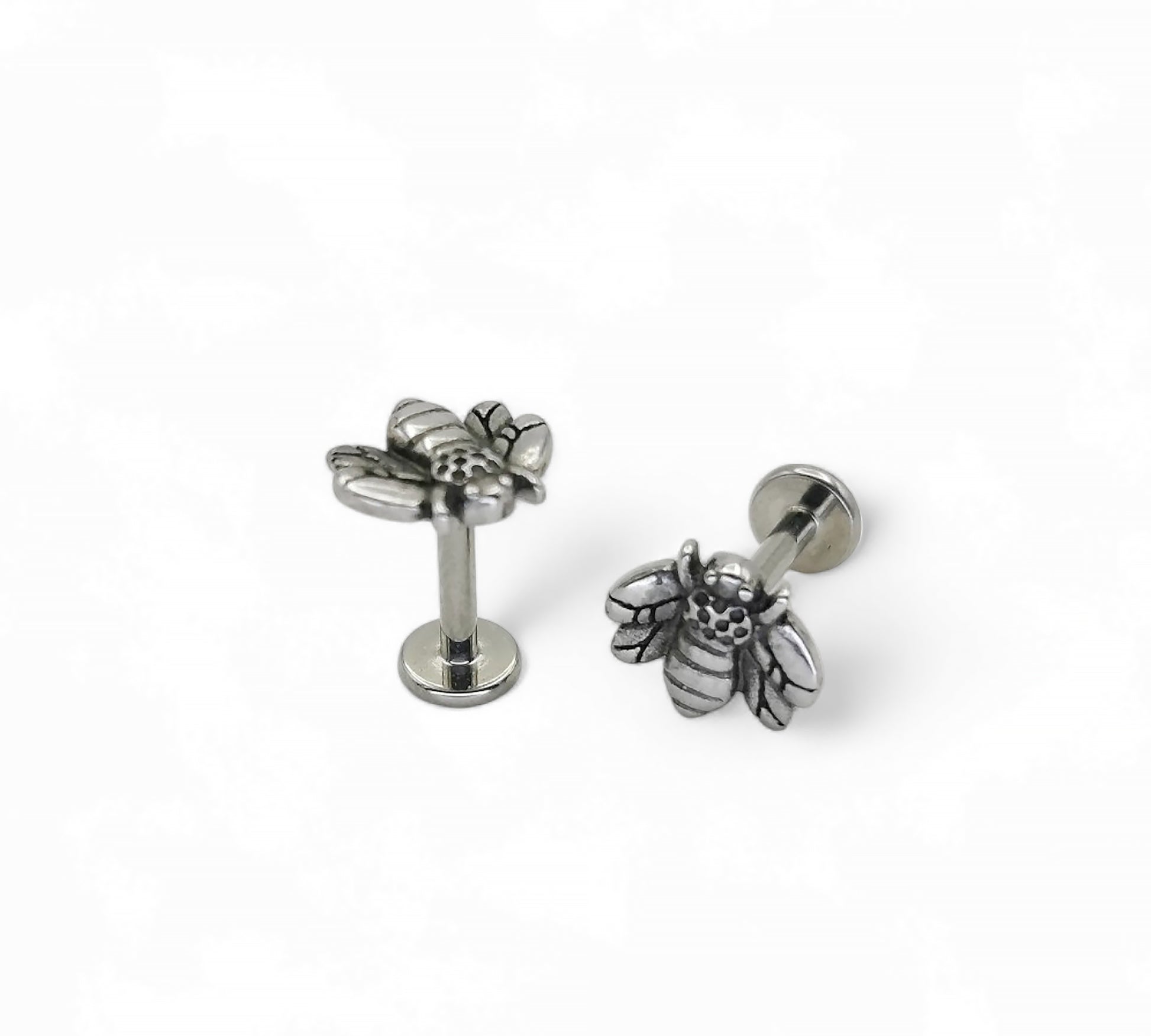 A high-polish finished titanium bee labret stud, with intricate details on the bee's wings and body, on a white background.