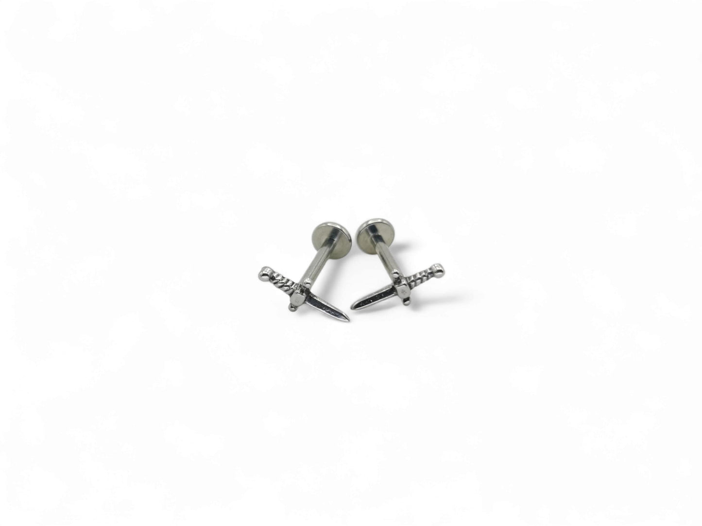 Two polished stainless steel dagger studs with a push fit mechanism for body jewelry, isolated on a white background.
