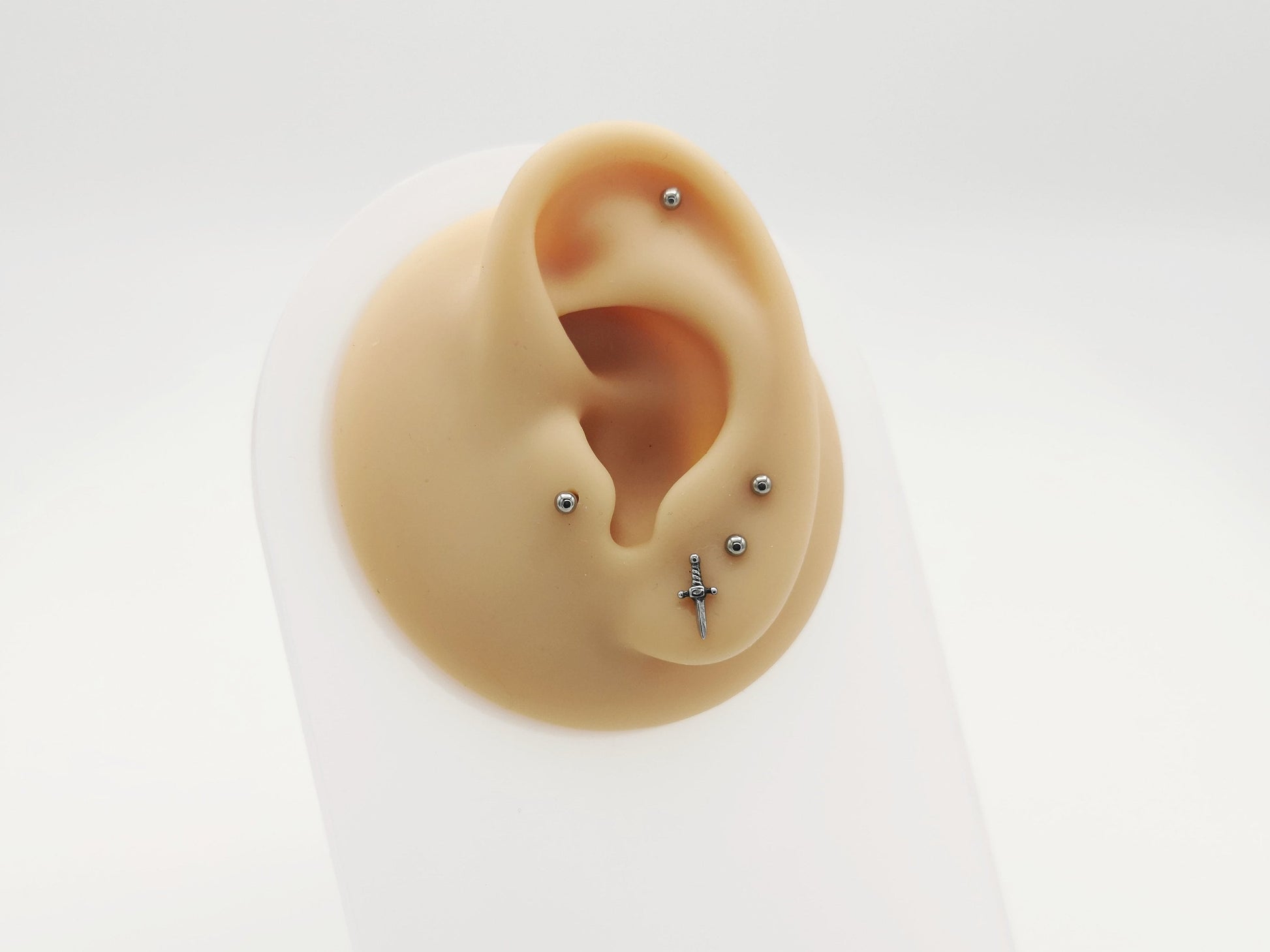 Two polished stainless steel dagger studs with a push fit mechanism for body jewelry, isolated on a white background.