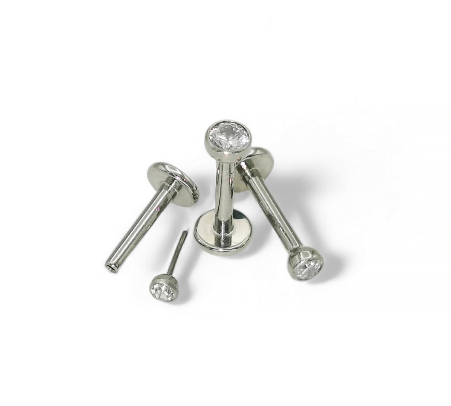 A selection of titanium push fit jewelled studs with bezel-set cubic zirconia in various sizes, displayed against a white background.