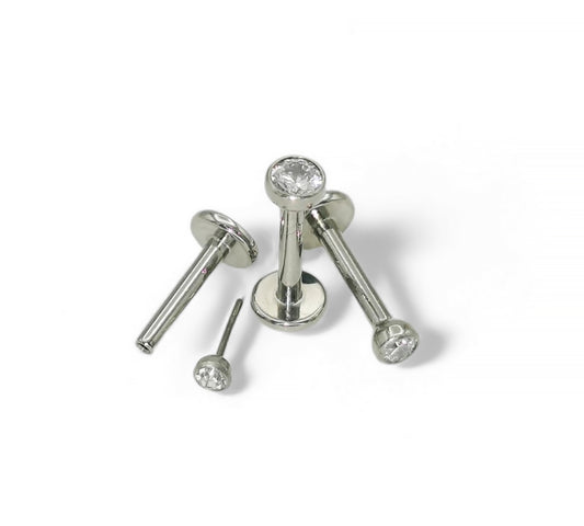 A selection of titanium push fit jewelled studs with bezel-set cubic zirconia in various sizes, displayed against a white background.