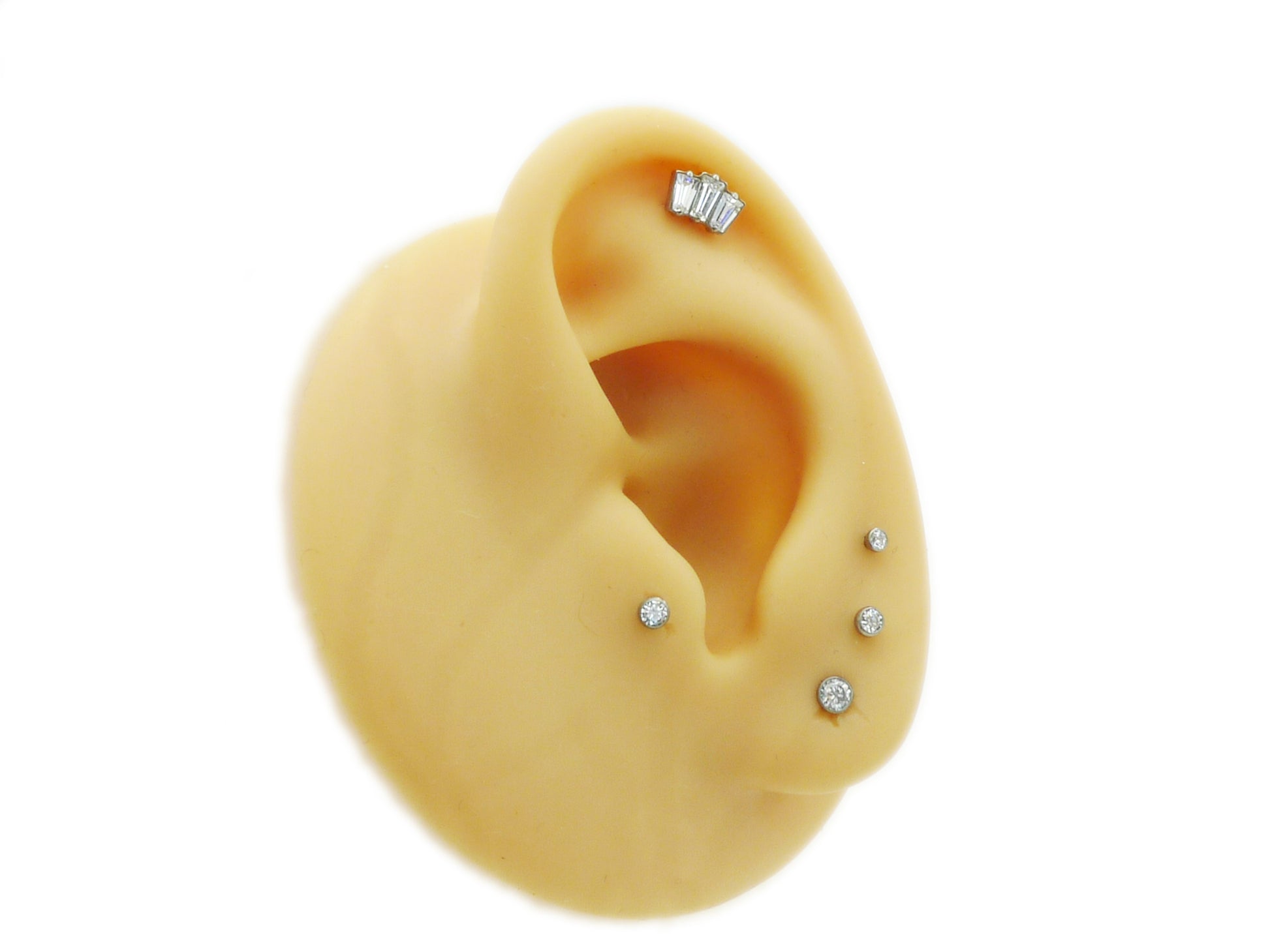 Model of an ear with multiple earrings on a white background