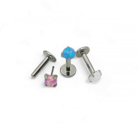 A collection of titanium push fit jewelled threadless studs in various colors including blue, pink, and clear, designed for use in multiple piercing types.