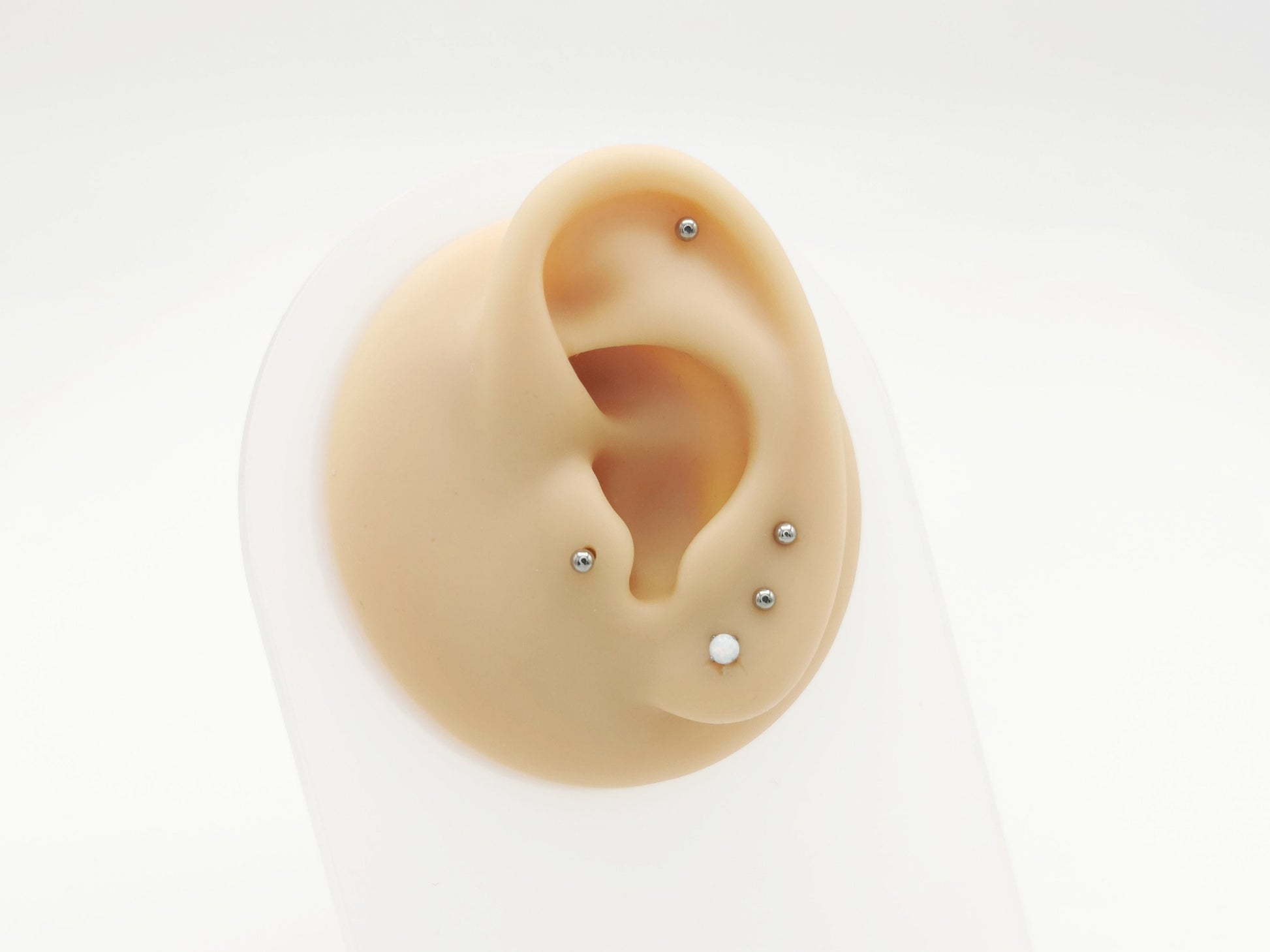 A collection of titanium push fit jewelled threadless studs in various colors including blue, pink, and clear, designed for use in multiple piercing types.