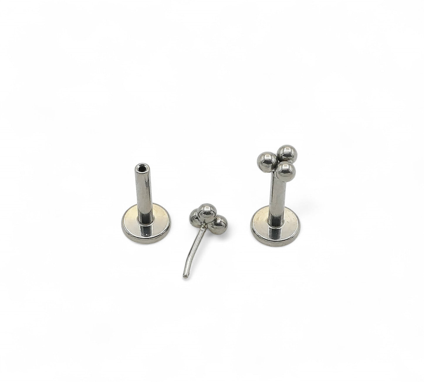 Set of three silver titanium push fit trinity studs on a white background