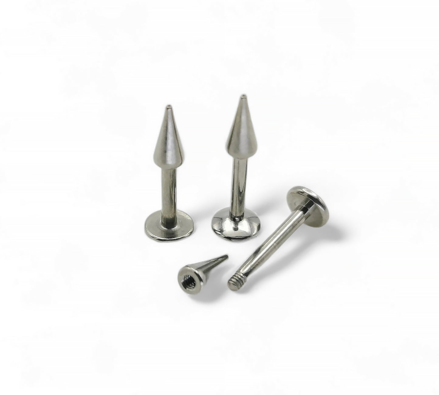 A collection of titanium spike labret studs in various lengths, with a flat disc back, displayed on a white background.