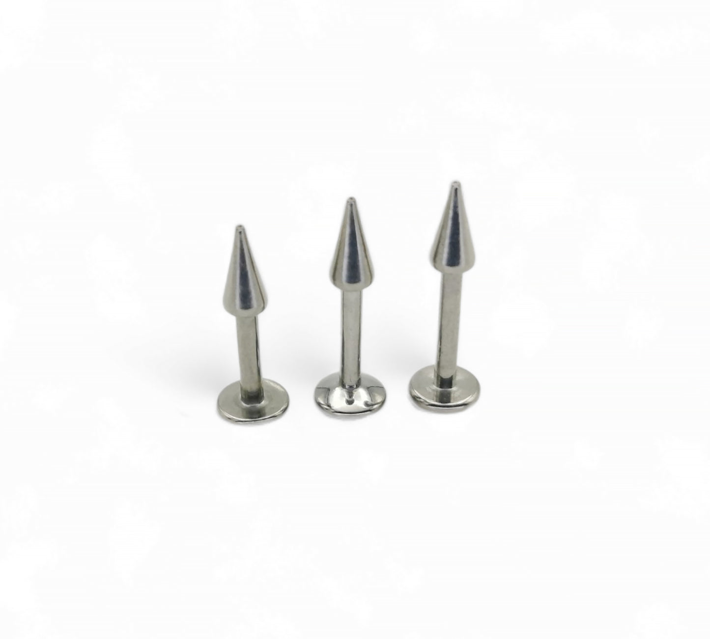 Three metallic spike pins on a white background
