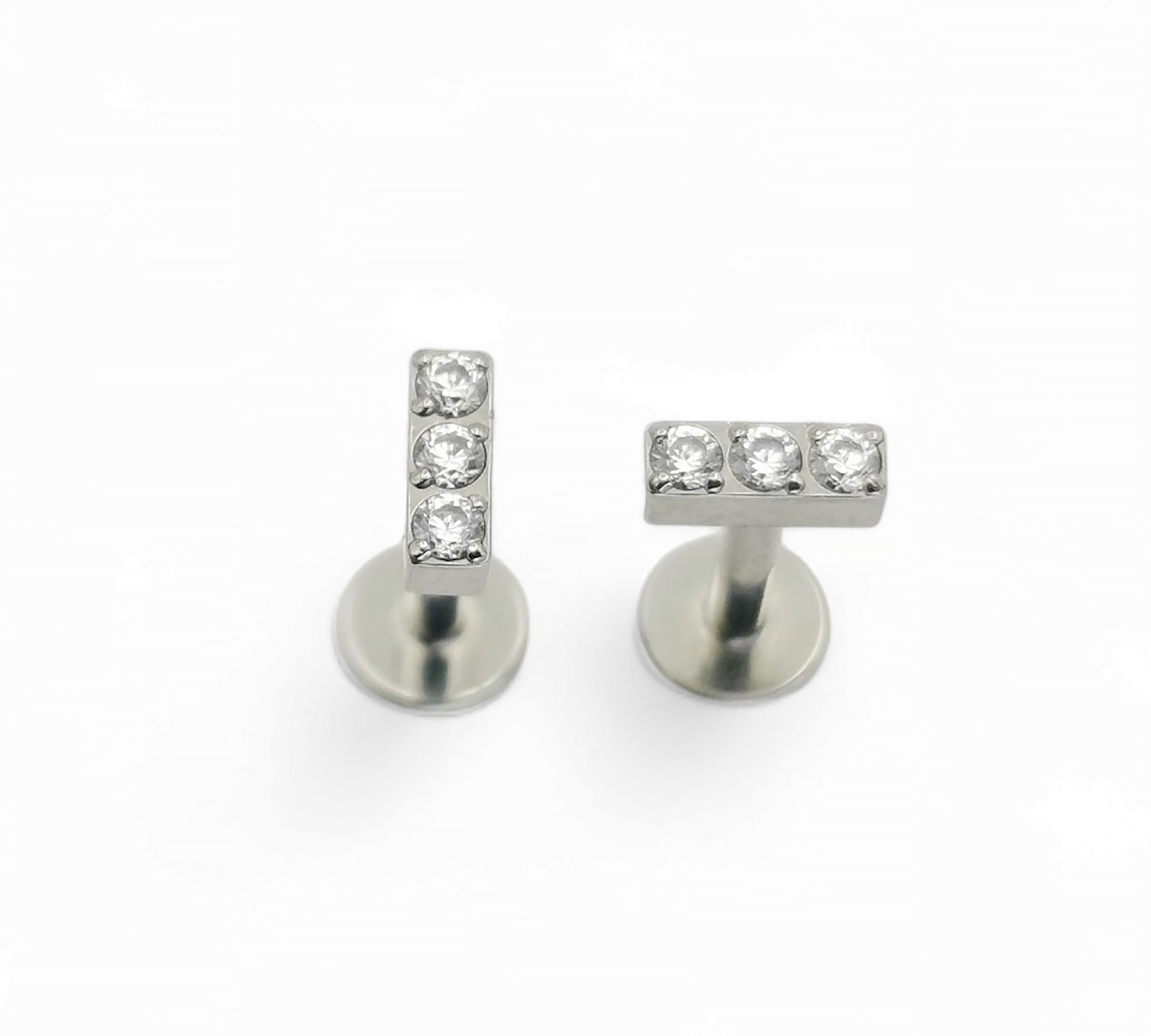 A pair of titanium threadless stud earrings with a triple CZ pave baguette design, presented against a white background.
