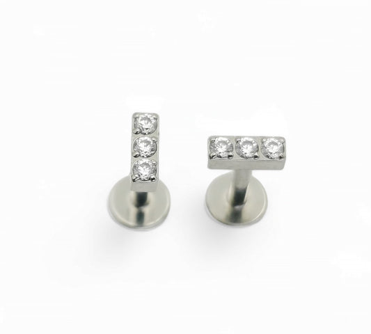 A pair of titanium threadless stud earrings with a triple CZ pave baguette design, presented against a white background.