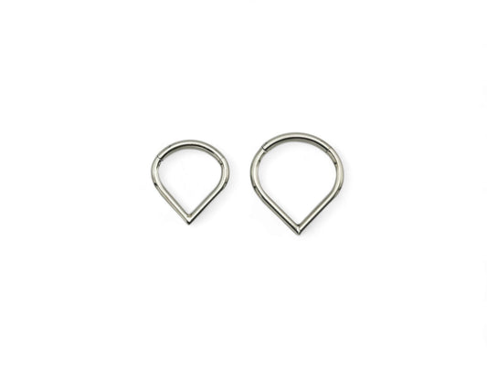 Two titanium wishbone clickers for piercings, with a shiny metallic finish, placed against a white background.
