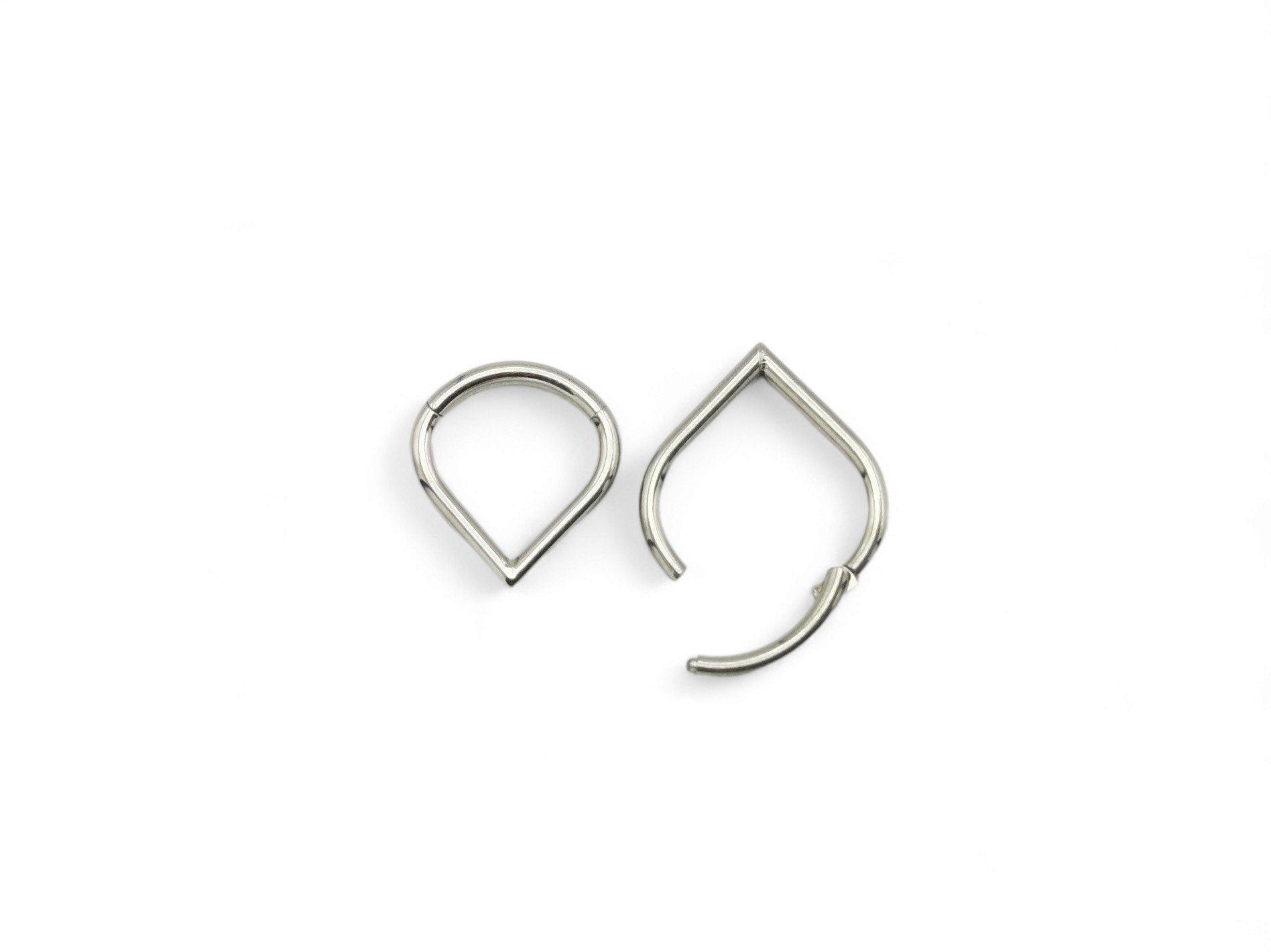 Two titanium wishbone clickers for piercings, with a shiny metallic finish, placed against a white background.