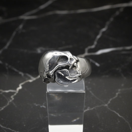 A sterling silver vampire bat skull ring displayed on a clear stand, with a plain grey background.
