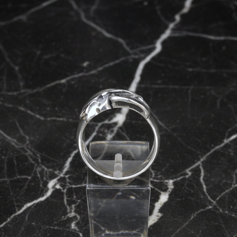 A sterling silver vampire bat skull ring displayed on a clear stand, with a plain grey background.